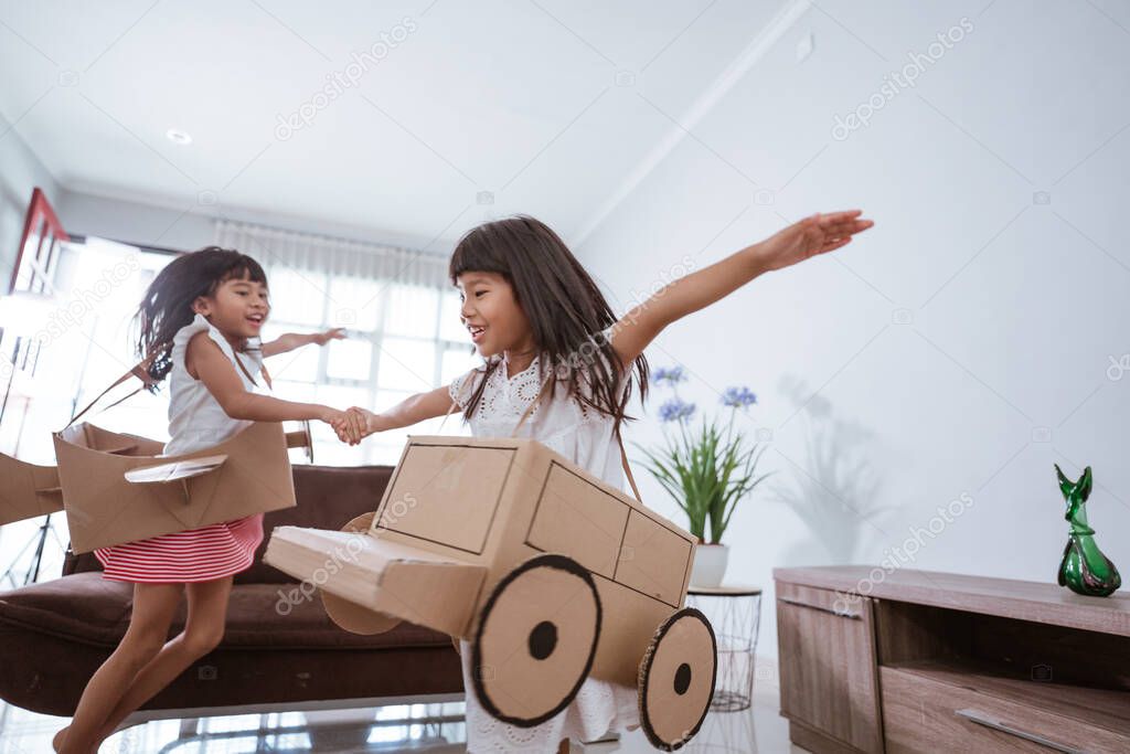 girl playing with cardboard toy airplane at home