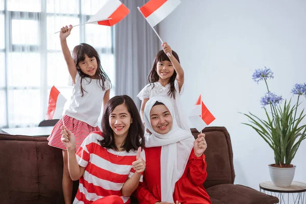 Madre e hija celebrando el día de la independencia indonesia en casa vistiendo de rojo y blanco con bandera de indonesia —  Fotos de Stock