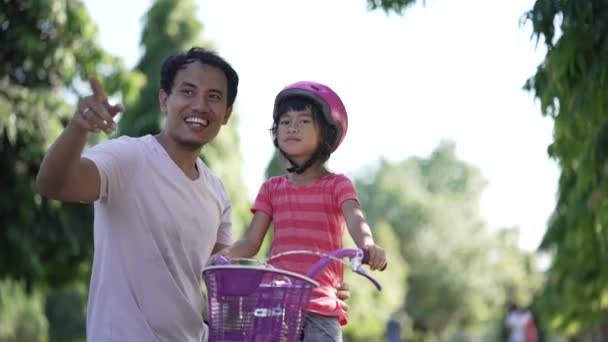 Baba kızına parkta bisiklet sürmeyi öğretiyor. — Stok video