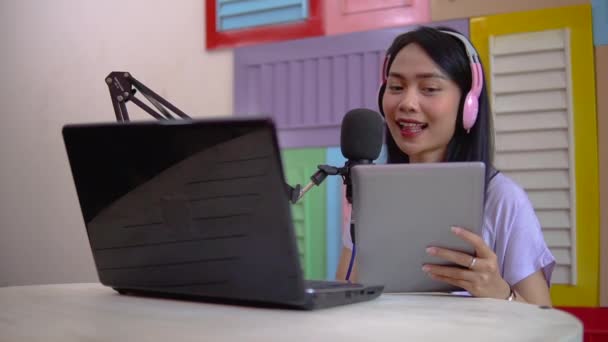 Woman using a pad and wearing headphones talking in front of a microphone — Stockvideo