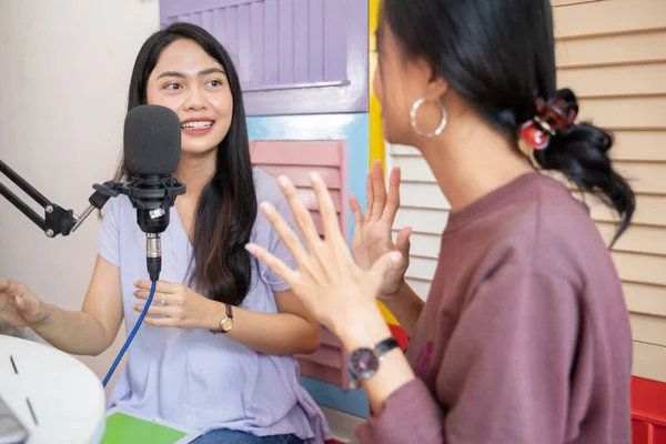 Two asian girls with hands gesture while chatting using microphone at podcast — Stockfoto