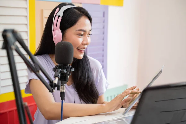 Cheerful girl using a tablet and wearing headphones with microphone equipment — Φωτογραφία Αρχείου