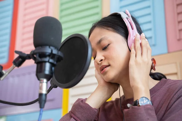 Close up of a cool asian girl listening wearing headphones during podcast — Stock fotografie