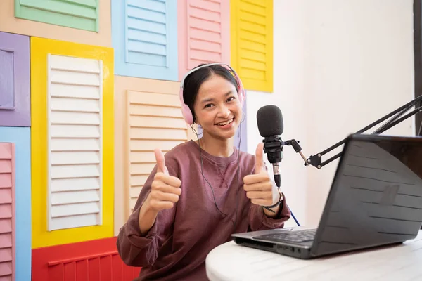 Asyalı kız mikrofonun önünde gülümserken başparmaklarıyla video blogu kaydediyor. — Stok fotoğraf