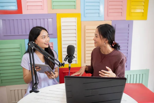 Dos mujeres charlando durante el podcast usando un micrófono y una tableta — Foto de Stock