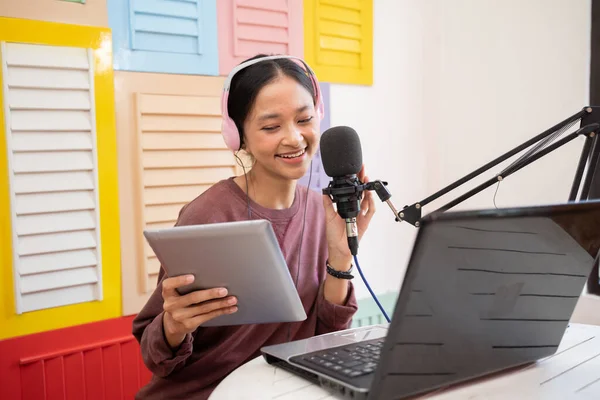 Woman speaking into microphone while recording video blog for her subscribers — Stock fotografie