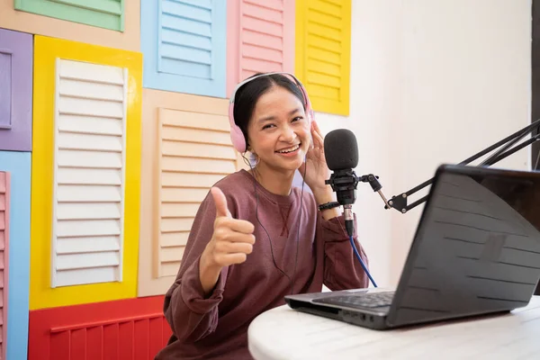 Una chica asiática hablando en el micrófono mientras la grabación de vídeo blog con los pulgares hacia arriba —  Fotos de Stock