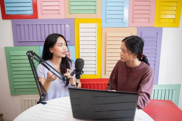 Two women talking seriously and using microphones while recording podcast — Stockfoto