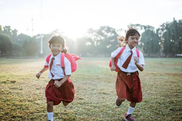 Bambina studentessa che corre insieme mentre va alla loro scuola — Foto Stock