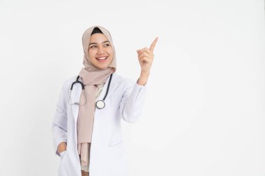 Başörtüsü takmış gülümseyen kadın doktor. Parmakla işaret ediyor.