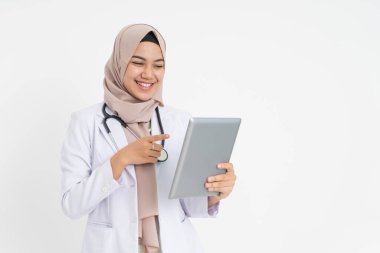 Beyaz takım elbiseli peçeli kadın doktor. Parmakla göstererek gülümsüyor.