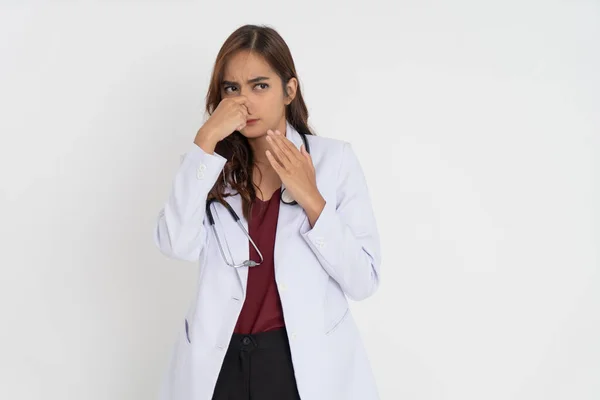 Medico donna che indossa uniforme tuta bianca si sente a disagio perché ha un cattivo odore coprendo il naso con la mano — Foto Stock