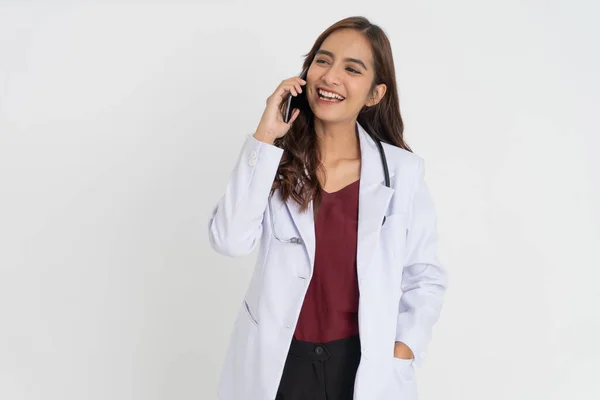 Un medico donna in uniforme bianca sorridente mentre fa una telefonata — Foto Stock