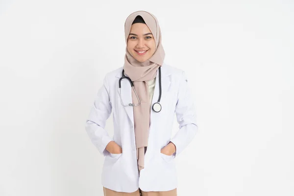 Başörtülü, neşeli, gülümseyen dişleri ve elleri cebinde çekici bir kadın doktor. — Stok fotoğraf