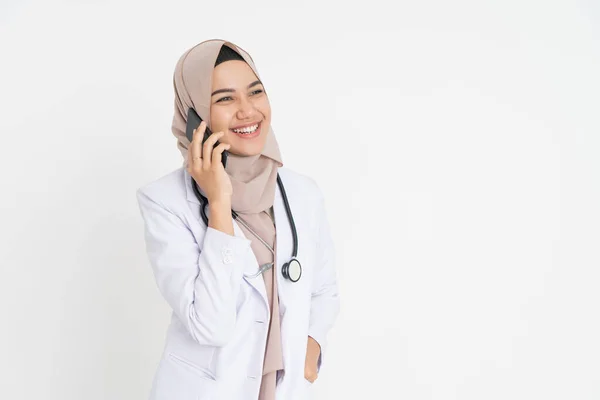 Médico con velo vistiendo traje blanco uniforme escuchando una llamada usando un teléfono móvil felizmente con copyspace —  Fotos de Stock