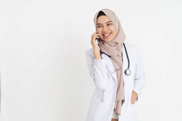 Zawoalowany lekarz w białym mundurze uśmiechnięty podczas rozmowy telefonicznej — Zdjęcie stockowe