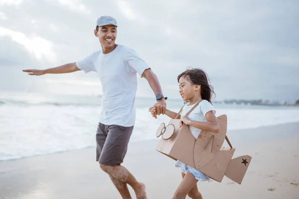 Père et enfant courir avec jouet avion en carton à la plage — Photo