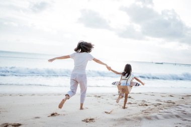 Anne kız el ele tutuşup karton uçakla koşuyor.
