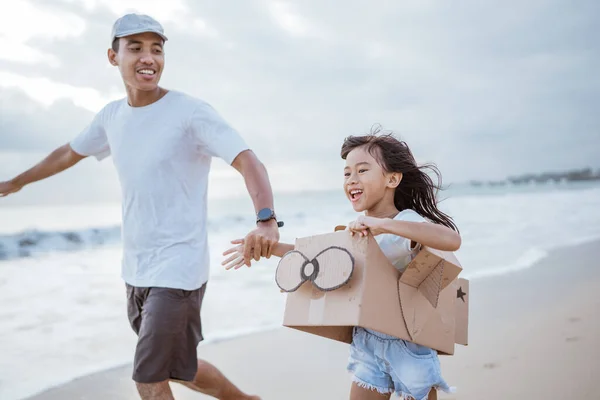 Père et enfant courir avec jouet avion en carton à la plage — Photo