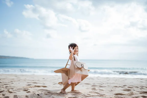 Dítě běží na pláži hrát s kartonem hračka letadlo — Stock fotografie