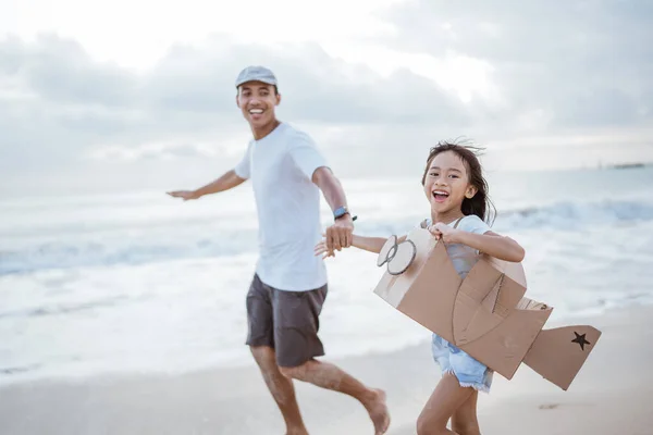 Asiático pai e filha correndo no praia jogar com papelão brinquedo avião — Fotografia de Stock