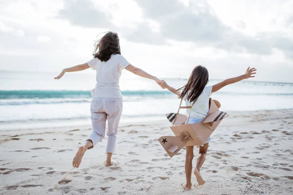 Mãe e filha brincando com avião de papelão na praia juntos — Fotografia de Stock