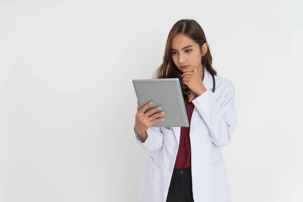 Femme médecin penser tout en regardant écran pad avec main tenant menton — Photo