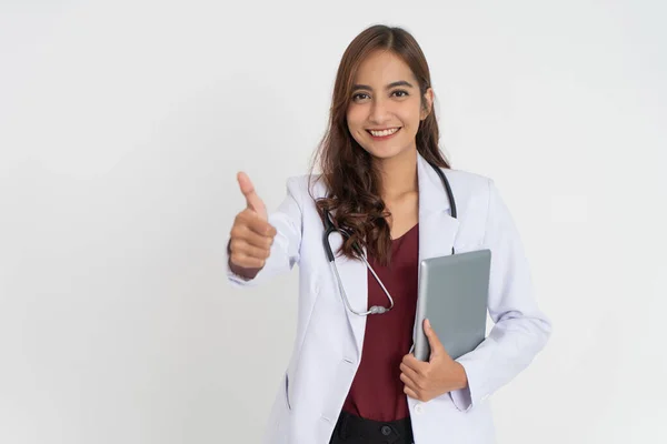 Aantrekkelijke vrouwelijke arts glimlachen tanden in uniform met duimen omhoog houden van een pad — Stockfoto