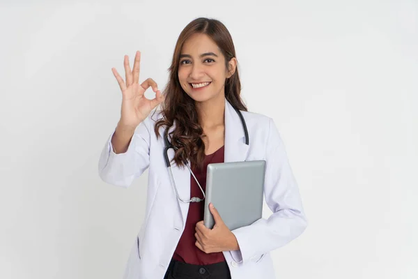 Привлекательная женщина-доктор улыбается зубами в униформе с символическим жестом, держа прокладку с пространством. — стоковое фото