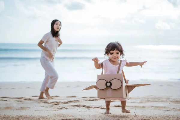 Adorável mãe e filha brincando com avião brinquedo de papelão — Fotografia de Stock