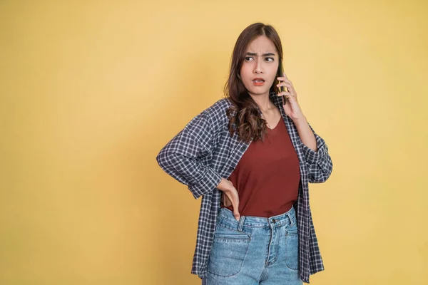 Uma mulher falando em uma chamada usando um telefone celular com uma expressão irritada — Fotografia de Stock