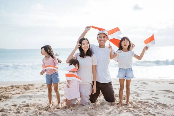 Torcedor da família indonésia animado com bandeira indonésia na praia juntos — Fotografia de Stock