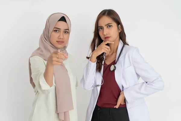 Пациентка в вуали с указательным жестом и красивый доктор в белой форме держа подбородок с выражением мысли — стоковое фото