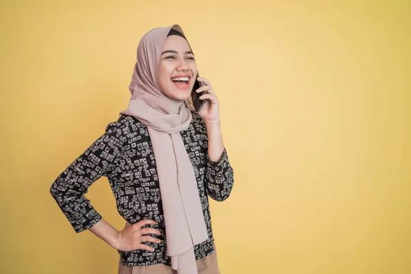 Jovem mulher em lenço de cabeça sorrindo amplamente e relaxando as mãos na cintura, enquanto recebendo uma chamada com gesto feliz — Fotografia de Stock