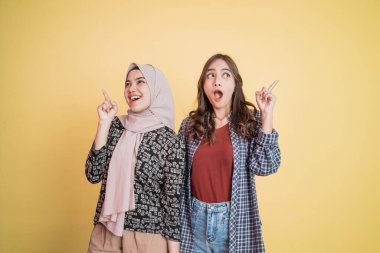 İki heyecanlı kadın parmak hareketleriyle yan yana duruyor. Kopyalama boşluğunu işaret ediyorlar.