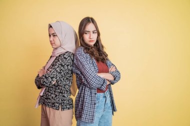 İki üzgün Asyalı kız sırt sırta verip kopyasıyla el ele tutuşmuşlar.