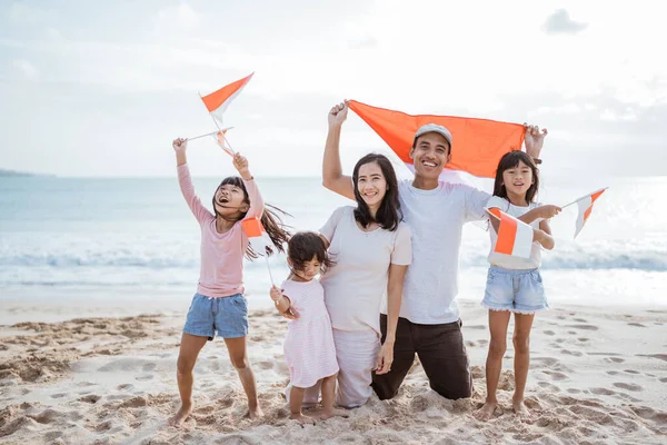 Izgatott indonéz család támogató indonéz zászló a strandon együtt — Stock Fotó