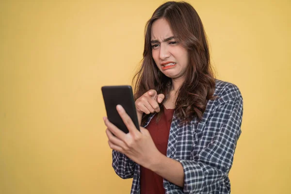 Primer plano de la mujer mirando a la pantalla mientras usa un teléfono inteligente con expresión disgustada —  Fotos de Stock