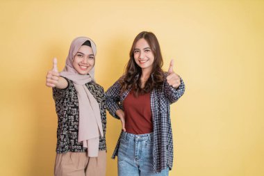 İki kadın kameraya gülümsüyor. Başparmakları havada, başparmakları havada.