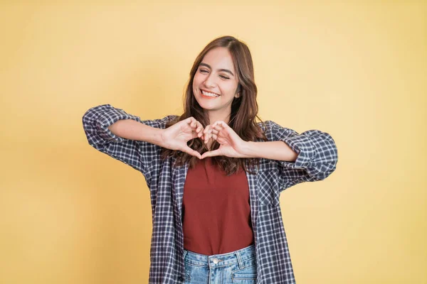 Jovem menina bonita alegre está gesticulando um coração com os dedos — Fotografia de Stock