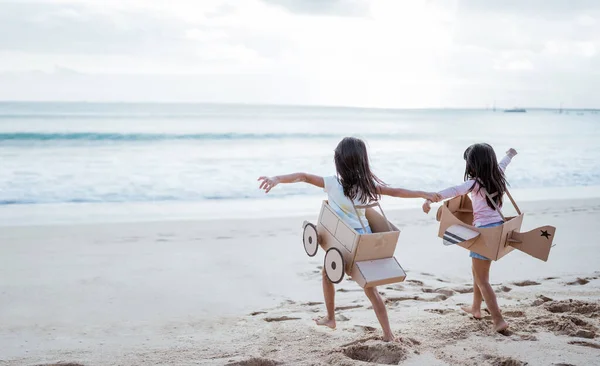 兄弟姐妹和女朋友在海滩上玩纸板飞机和汽车 — 图库照片