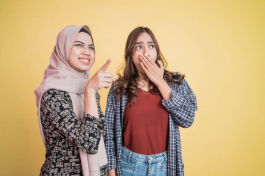 İki kadın şaşırmış bir şekilde hareket ediyor ve boşluğu işaret ediyor.