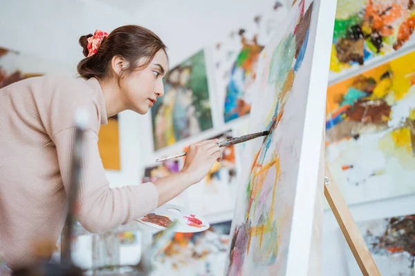 Kvinnlig konstnär arbetar på sin målning i studio — Stockfoto