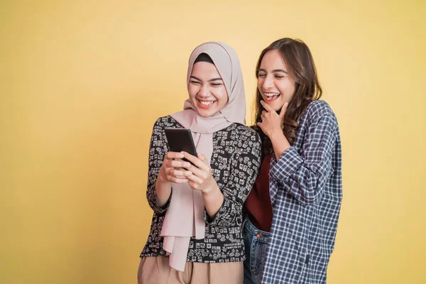 Mutlu iki Asyalı kadın cep telefonu kullanır ve telefon ekranını gördüklerinde şaşırırlar. — Stok fotoğraf