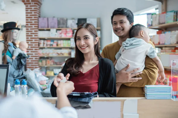 Famille effectuant un paiement à la boutique de bébé en utilisant la carte de crédit à la caisse — Photo