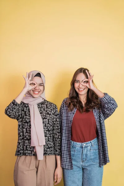 Zwei lächelnde Frauen mit o.k. zustimmender Handgeste auf einem Auge mit Kopierraum oben — Stockfoto