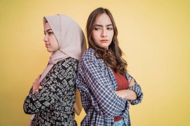 Sırt sırta verip el ele tutuşan iki üzgün kıza yaklaş.