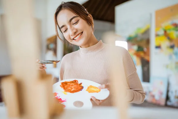 Vrouwelijke kunstenaar werkt aan haar schilderij in atelier — Stockfoto