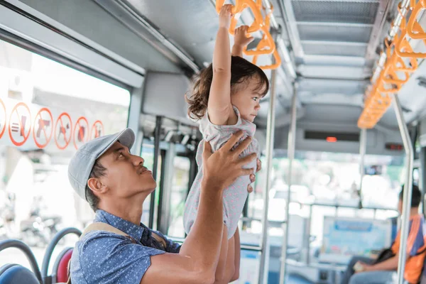 Батько і його дочка грають під час їзди на громадському транспорті, що звисає на барі — стокове фото