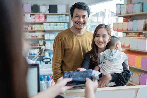 Familie die een betaling doet in de babywinkel met een creditcard bij de kassier — Stockfoto